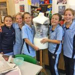 students together with their finished mannequin design, using only newspaper